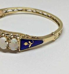 Estate 9 Oval Opal Royal Blue Floral Flower Enamel Hinged 14k YG Bangle BraceletMaterial: 14k yellow gold, stampedWeight: 18.5 gramsDiameter: 2 1/2"Size: 10mm wide (top of bracelet)2 3/4" long (safety chain)Stones: 9 oval opals 7 x 5mm each (all opals are slightly over 7 x 5mm), all in perfect conditionRoyal blue enamel on both sides with a flower design in centerAll original enamel in perfect conditionHallmarked: 14k This is an estate piece in excellent condition, it is in it's original worn st Yellow Gold Multi-stone Oval Bracelet, Yellow Gold Multi-stone Oval Bracelets, Yellow Gold Oval Bracelet With Multi-stone, Yellow Gold Oval Multi-stone Bracelet, Oval 14k Yellow Gold Bracelet, Heirloom Gold Multi-stone Bracelets, Fine Jewelry Yellow Gold Multi-stone Bangle, Heirloom Gold Bracelets With Multi-stone, Yellow Gold Multi-stone Bangle In Fine Jewelry Style