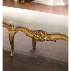 an ornate gold bench with white fabric on it