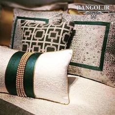 three decorative pillows sitting on top of a white bed with green trimmings and beading