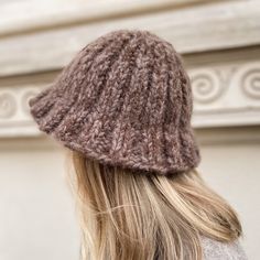 a woman with blonde hair wearing a brown knitted hat