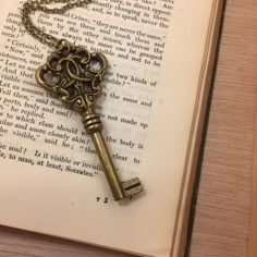 an antique key is sitting on top of an open book