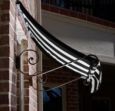 a black and white striped umbrella hanging from the side of a brick building in front of a window