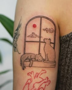 a woman with a tattoo on her arm has a cat and dog looking out the window