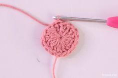 the crochet pattern is being worked on by someone using a pink yarn needle