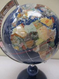 the globe is on top of a stand with a blue base and red trim around it