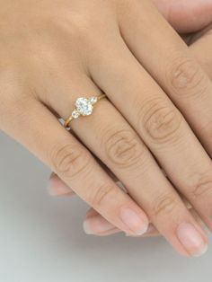 a woman's hand with a diamond ring on top of her finger and the other hand holding it