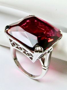 Simulated Red Ruby RingE-Ring Design#D1 This is a beautiful vintage reproduction ring. The sterling silver filigree holds an ~20 carat simulated red ruby gemstone. The man-made gemstone has perfect ruby red color and amazing clarity. The flawless high-quality square-cut gemstone is 18mm square. The stone and setting rise about 1/2" off the finger. The inside of the band is marked 925 for sterling silver. Notice the beautiful crisscross basket pattern in the silver filigree setting. This geometri Red Art Deco Jewelry For Formal Occasions, Ruby Rings For Party, Fine Jewelry Style, Classic Rings With Accent Stones For Party, Elegant Ruby Ring For Party, Classic Party Rings With Accent Stones, Elegant Party Ruby Ring, Elegant Red Ruby Ring In Sterling Silver, Classic Emerald Cut Rings For Party, Formal Red Diamond Cut Ring