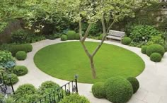 a circular garden with trees, bushes and benches in the center is surrounded by shrubbery