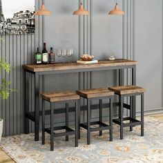 three stools and a table with bottles on it in front of a gray wall