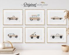 four framed pictures with cars on them in front of a white wall and a potted plant