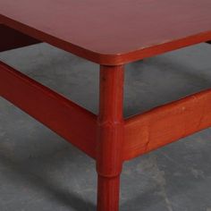 a red wooden table sitting on top of a cement floor