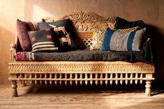 a couch with many pillows on it in front of a wooden paneled wall and floor