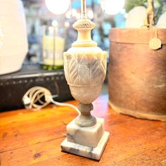 a white lamp sitting on top of a wooden table next to a potted plant