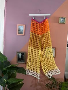 an orange and yellow net hanging from a hook on a purple wall next to a potted plant