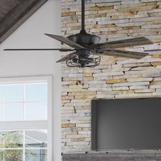 a ceiling fan in front of a brick wall with a flat screen tv on it