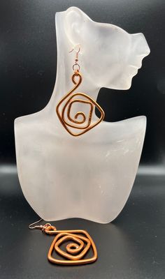 a pair of earrings sitting on top of a white piece of glass next to a black background