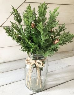 a mason jar filled with pine cones and greenery