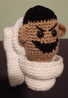 a crocheted stuffed monkey with a scarf around its neck and eyes on it's head