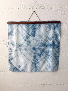 a blue and white tie - dyed wall hanging on a brick wall with a wooden hanger