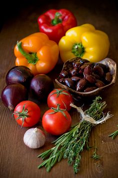 several different types of vegetables sitting on a table next to garlic, tomatoes, and peppers