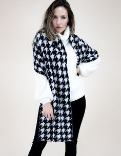 Elevate your style with our Chic Houndstooth Scarf in classic black and white. Made from a soft and warm wool-blend fabric, this scarf adds a touch of sophistication to any outfit. Its timeless houndstooth pattern never goes out of style and complements any color scheme.  At 69.00x20.00 inches, this scarf is versatile in length and can be styled in multiple ways - looped around the neck, draping over the shoulders, or wrapped for extra warmth. It also features delicate fringe detailing, adding a stylish touch to this must-have accessory. Why choose our Houndstooth Scarf? Its elegant design is perfect for any occasion, from a casual day out to a formal event. It also makes for a thoughtful and stylish gift, packaged beautifully and ready to be received with joy. To maintain its softness and Houndstooth Scarf, Winter Wrap, Winter Shawl, White Fringe, Cozy Scarf, Oversized Scarf, White Houndstooth, Houndstooth Pattern, Stylish Gifts