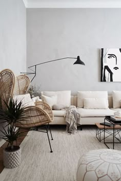 a living room with wicker furniture and art on the wall, including a white couch