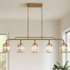 a chandelier hanging from the ceiling in a dining room with white walls and windows