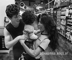 a man holding a baby in his arms while standing next to a woman at a grocery store