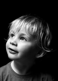 a black and white photo of a little boy looking up at something in the air