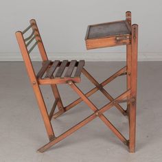 an old wooden folding chair with a tray on it's back and foot rest