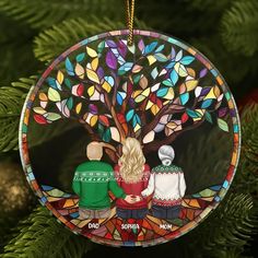 a glass ornament depicting two people sitting under a tree