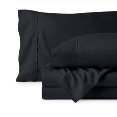 the black sheets and pillowcases are folded on top of each other, with two pillows