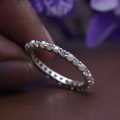 a close up of a person's hand holding a wedding ring with pearls on it