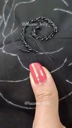 a person's hand with a red nail polish next to a chain