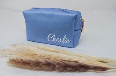 a small blue bag sitting on top of a white table next to a feather tail