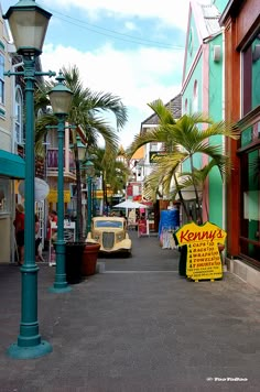 an old car parked on the side of a street next to a lamp post and palm trees