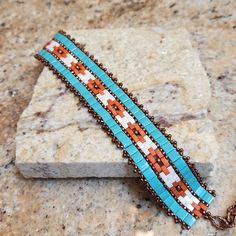 This stunning statement bracelet is handcrafted with glass beads that are woven to create the geometric Southwest design.  The band is approximately 1 inch wide and the bead-woven portion is 6 1/2 inches long.  It can be worn as a 7 inch and up to a 8 1/4 inch size due to the versatile extender chain.  The bracelet features the soft muted colors of a desert palette.  This is truly a unique piece to add to your jewelry collection or to give as a special gift. Adjustable Southwestern Bracelets As Gift, Adjustable Southwestern Style Bracelets As Gift, Adjustable Southwestern Style Bracelets For Gifts, Turquoise Beaded Cuff Bracelet For Gift, Turquoise Beaded Bangle Friendship Bracelets, Handmade Turquoise Beaded Bangle Bracelet, Turquoise Bangle Beaded Bracelet For Gift, Turquoise Beaded Bangle Bracelet Gift, Turquoise Beaded Bangle Bracelet For Gift