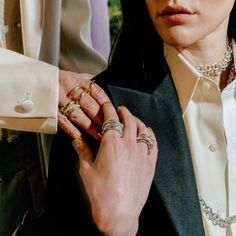 a woman in a suit and some rings on her finger, holding onto another person's jacket