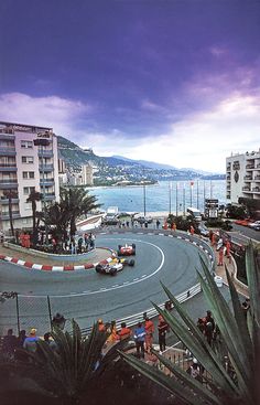 an aerial view of a race track with cars driving on it and people standing around