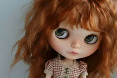 a close up of a doll with red hair and green eyes, wearing a dress