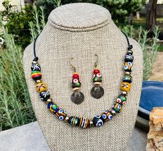 A variety of colorful African Krobo beads are interspersed with brass spacers and stringed on leather. Double-sided brass scarab charms dangle from matching earrings. Length of earrings: 1.75 inches. Handmade Multicolor Brass Beaded Necklaces, Handmade Multicolor Brass Beaded Necklace, Multicolor Brass Beaded Necklaces As Gift, Multicolor Brass Jewelry With Dangling Beads, Multicolor Round Beaded Brass Jewelry, Multicolor Dangle Jewelry With Wooden Beads, Eclectic Wooden Beads Jewelry Gift, Adjustable Eclectic Jewelry With Wooden Beads, Eclectic Adjustable Jewelry With Wooden Beads