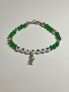 "This is a handmade beaded bracelet for all those boy moms out there!! Very cute green and silver color with words \"Boy Mom\" and a cute little boy accent charm on a stretchy elastic with clasp. Would fit a 7\" wrist or bigger easily.   The silver beads really make the charm shine! Picture taken in different lighting to show how it looks under different settings. We offer free shipping on all of our items! If you are interested in a certain color combination, please send me a private message to Cute Green Stretch Bracelet With Round Beads, Cute Green Round Beads Stretch Bracelet, Casual Name Bracelet With Round Beads For Birthday, Casual Birthday Name Bracelet With Round Beads, Green Letter Beads Jewelry For Birthday, Personalized Green Bracelets As Gifts, Green Jewelry With Letter Beads For Birthday, Casual Round Beads Jewelry For Birthday, Nickel-free Green Beaded Bracelets For Gift