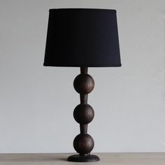 a lamp with three balls on it sitting on a table next to a white wall