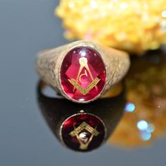 A gentleman's 10 karat yellow gold Masonic ring set with a 12 millimeter by 10 millimeter oval red spinel stone.  This ring is a size 10.5 Heirloom Red Gold Signet Ring, Heirloom Red Signet Ring With Polished Finish, Classic Red Signet Ring For Formal Occasions, Oval Ring With Maker's Mark For Gift, Classic Red Oval Cabochon Signet Ring, Classic Oval Engraved Ruby Ring, Classic Red Signet Ring Stamped 14k, Antique Red 14k Gold Signet Ring, Antique Red Signet Ring In 14k Gold