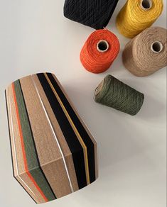 three skeins of yarn and two spools of thread on a white surface