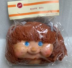 a plastic doll with blue eyes and brown hair wrapped in plastic on top of a table