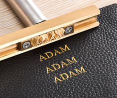 a close up of a black and gold folder with the word adam written on it