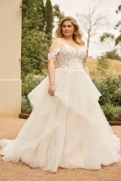 a woman in a white wedding dress posing for the camera with her hands on her hips