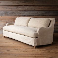 a couch sitting on top of a hard wood floor next to a wall with wooden planks