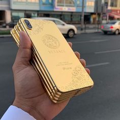 a person holding up a gold iphone case in the middle of an empty city street